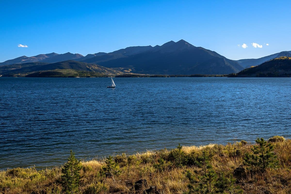 A sailboat crossing Twin Lakes Reservoir beneath the Sawatch Range in autumn light.