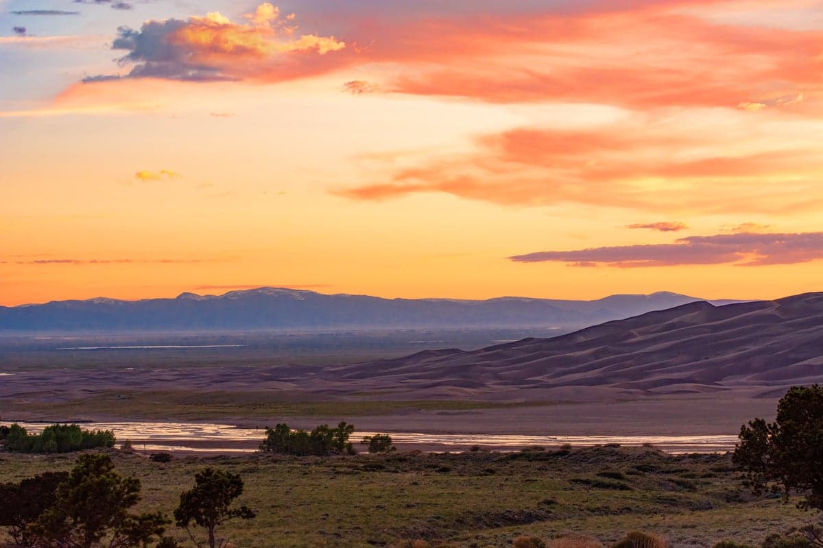 Sunset light over Medano Creek and the dune field at Great Sand Dunes National Park.