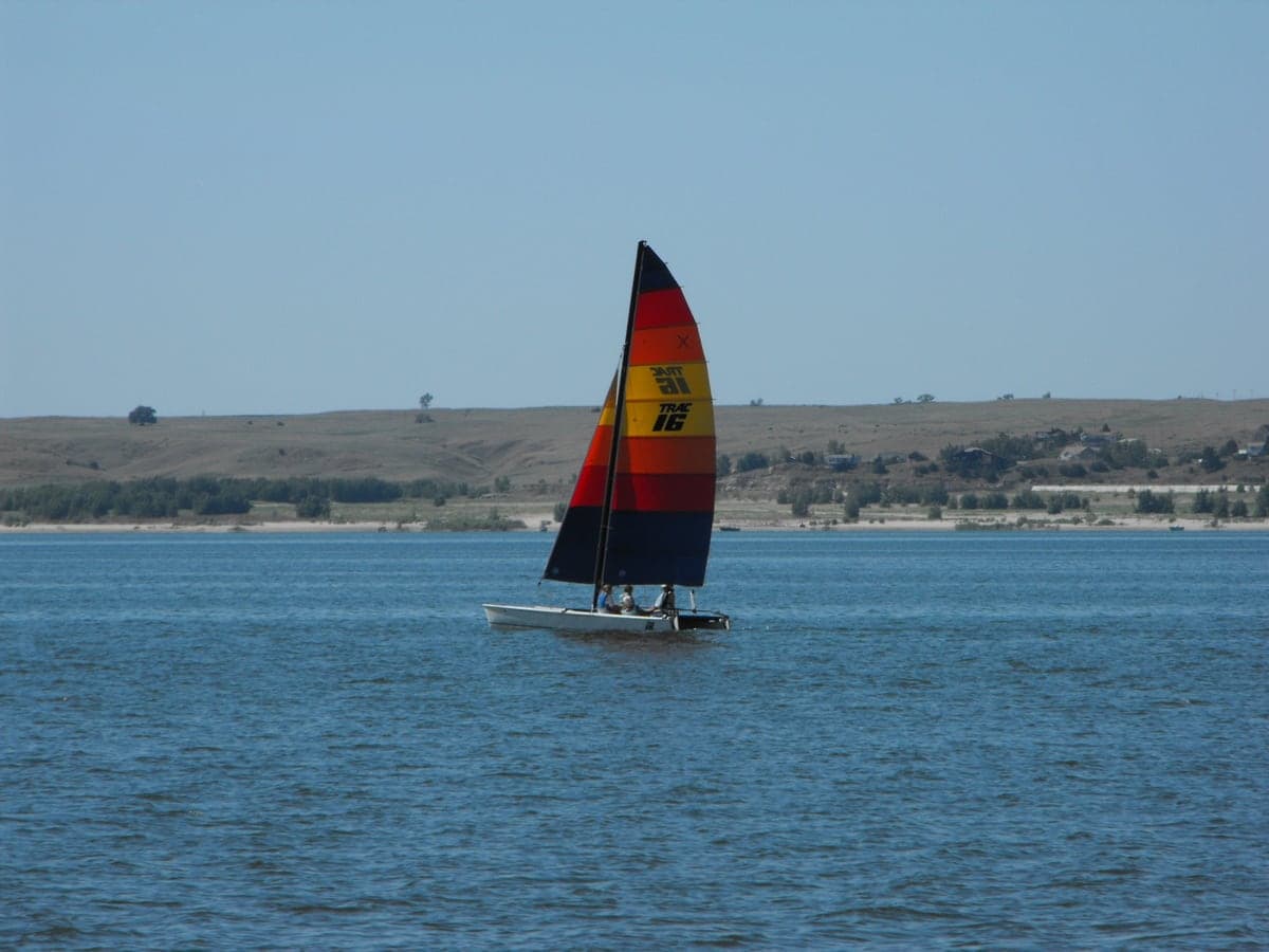 A catamaran sailboat crosses the broad blue water of Lake McConaughy.