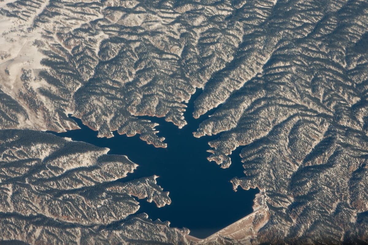 Aerial view of Rampart Reservoir surrounded by forested foothills near Pikes Peak.