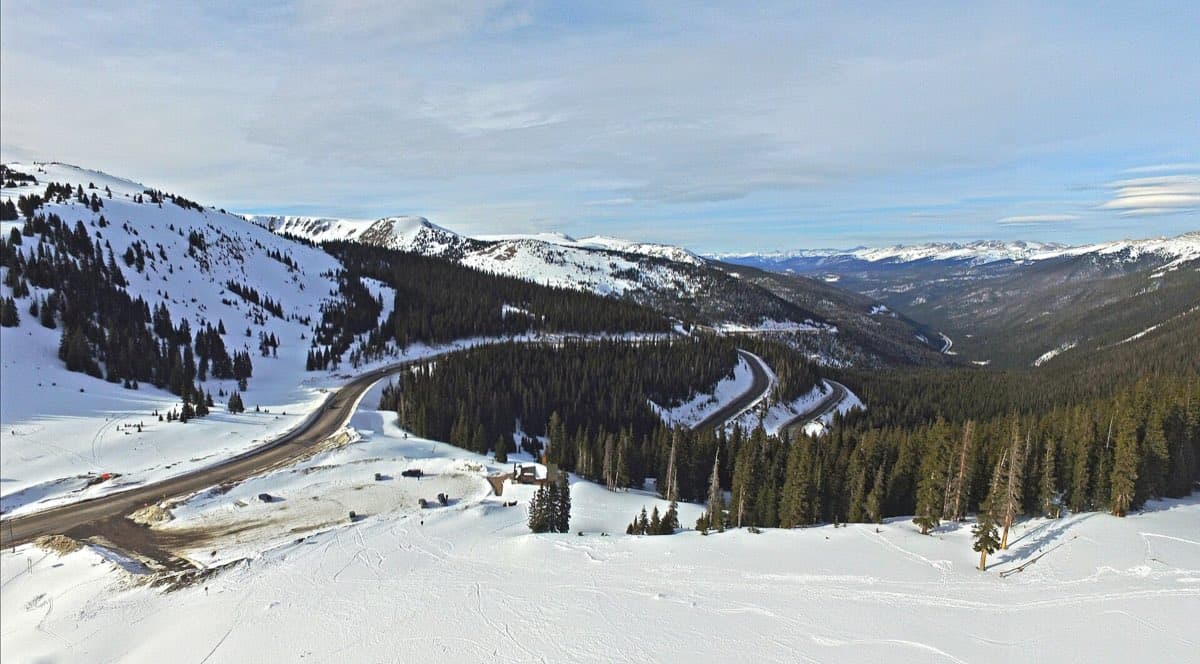 Snow-covered slopes and the winding US 40 corridor descending from Berthoud Pass into the Fraser Valley.