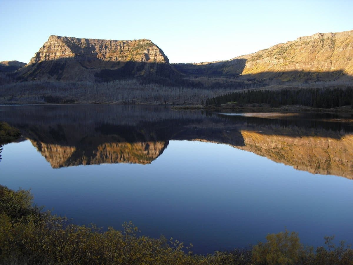 Soft sunrise light reflects across Trappers Lake beneath the Flat Tops plateau.