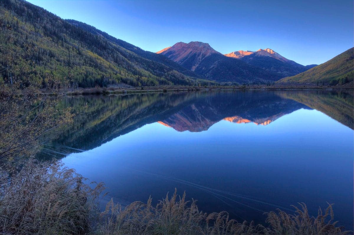 Sunrise reflects across Crystal Lake in the San Juan Mountains south of Ouray.