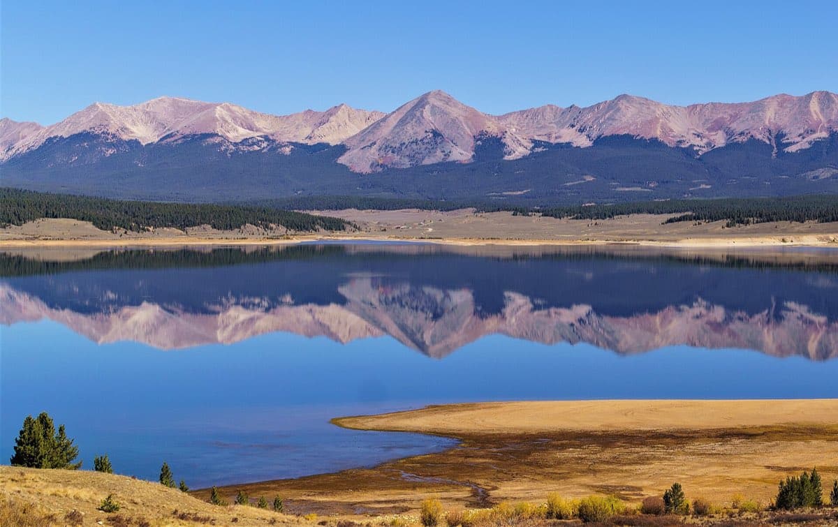 Taylor Park Reservoir reflects the Continental Divide, with Grizzly Peak centered above the calm water.