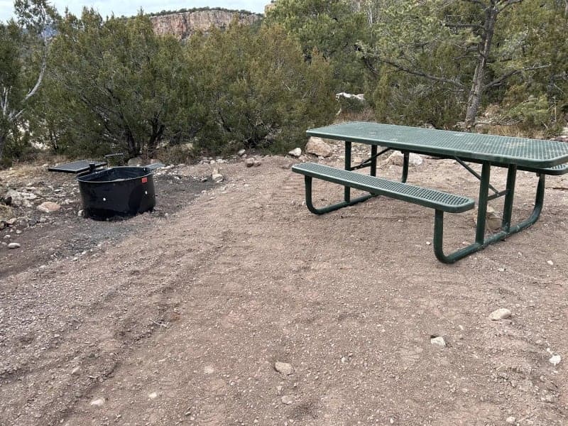 Picnic table and fire ring at Site 21 beneath Shelf Road cliffs in Sand Gulch Campground