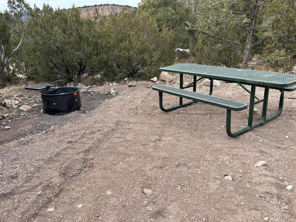 Picnic table and fire ring at Site 21 beneath Shelf Road cliffs in Sand Gulch Campground