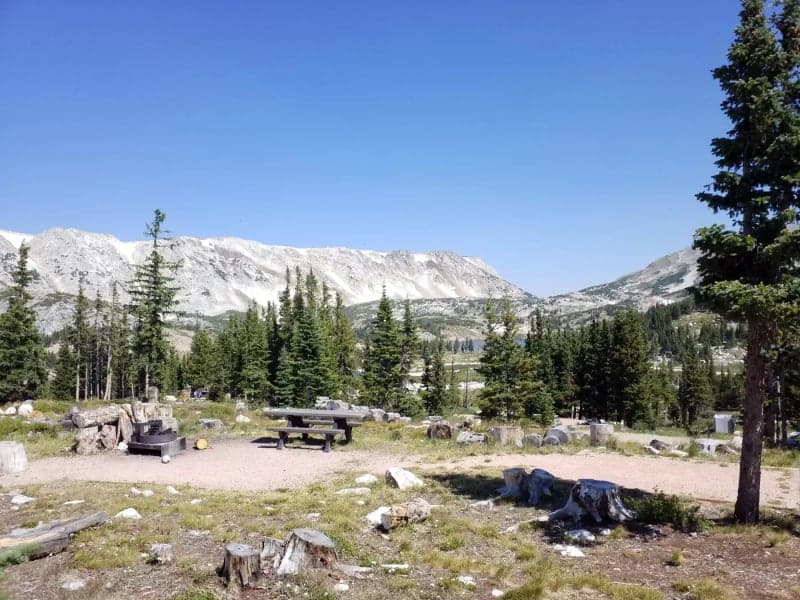 Picnic table, fire ring, and Medicine Bow mountain view from site 10 at Sugarloaf Campground