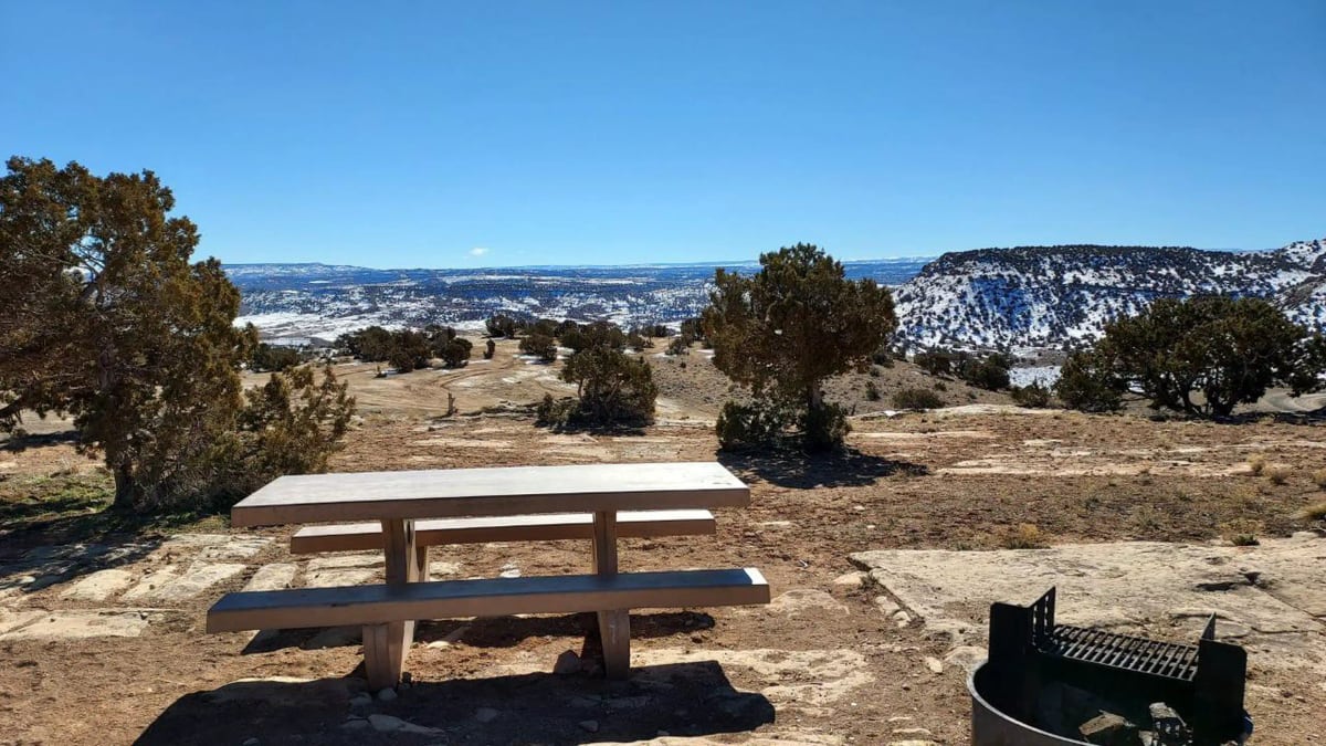 Picnic table and fire ring with snowy canyons in background