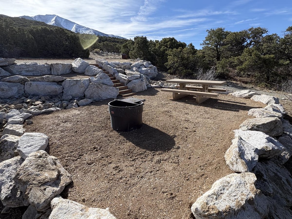 Picnic table and fire ring in a rock-lined site at Zapata Falls Campground