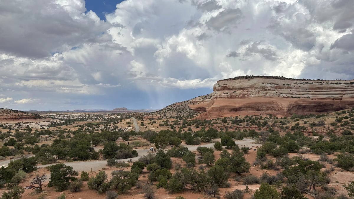 Windwhistle Campground campsites and gravel roads beneath Navajo sandstone cliffs and storm clouds