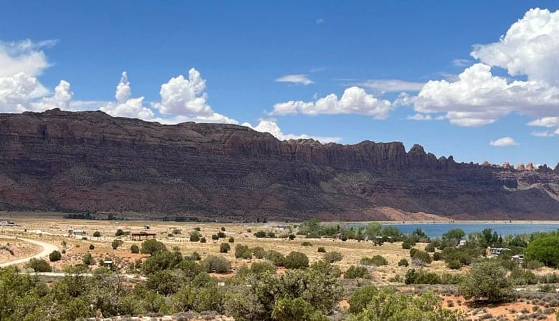Overview of Ken's Lake Campground below red-rock cliffs and summer clouds
