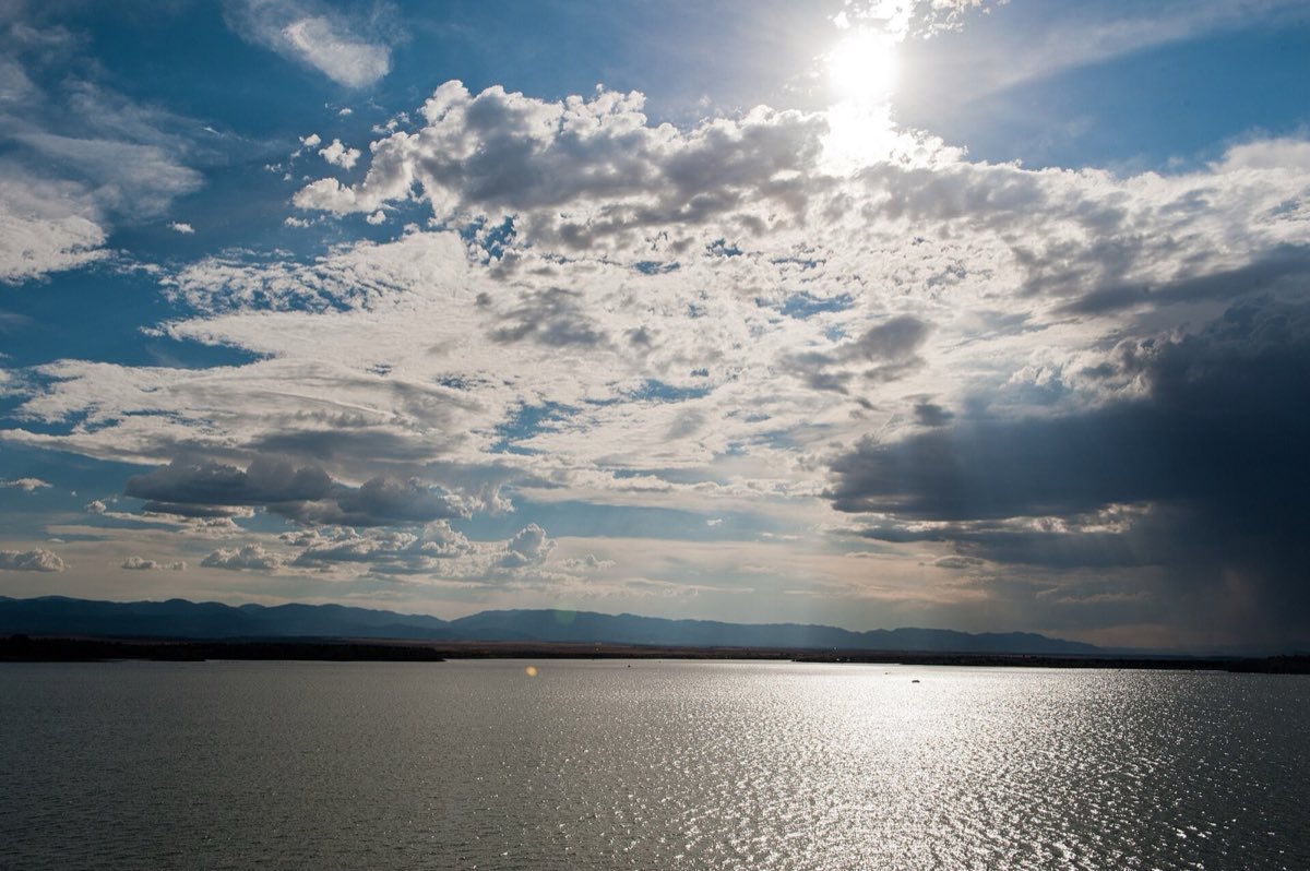 Late-afternoon light warms the blue water and dry hills around Lake Pueblo.