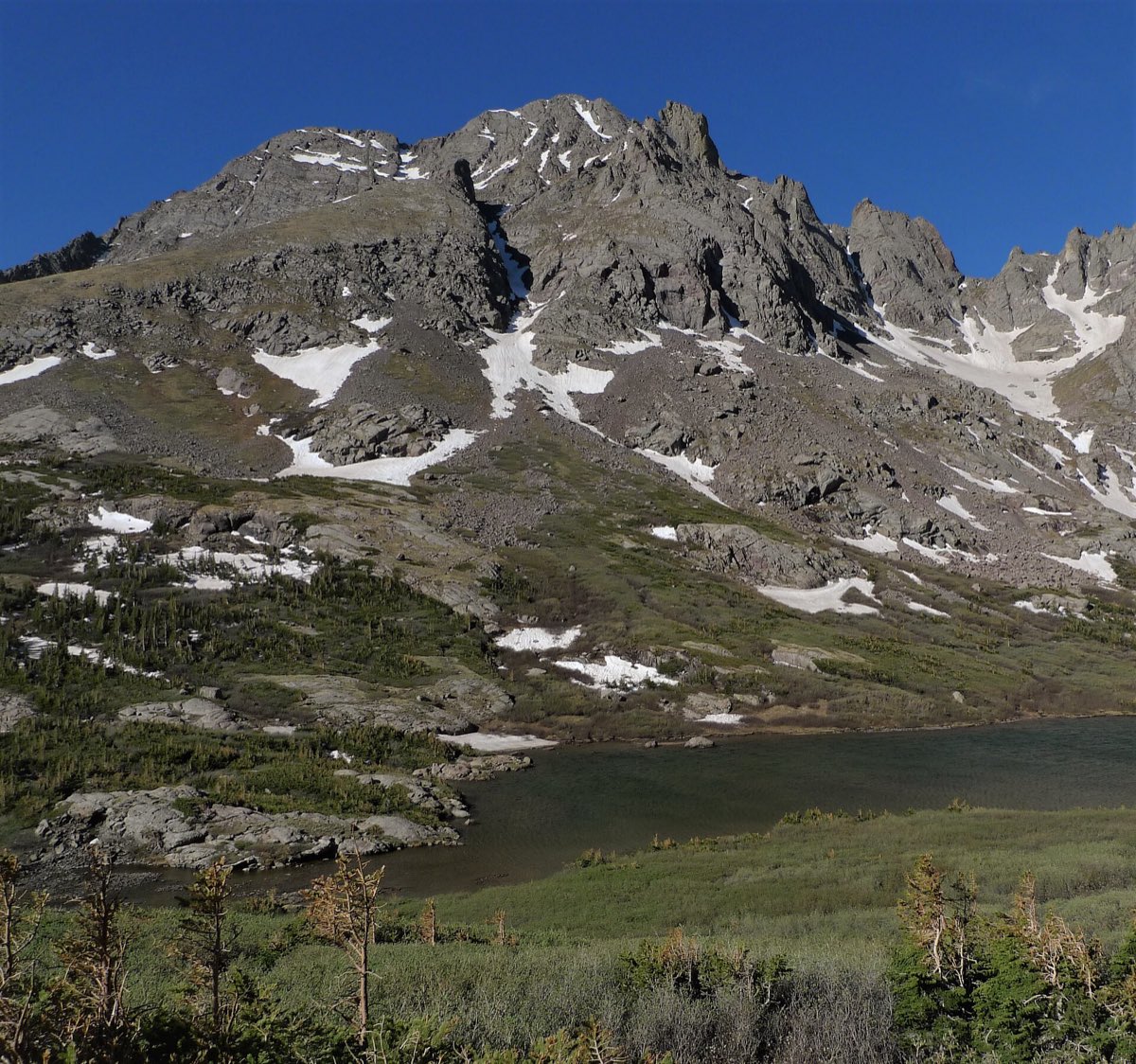 Broken Hand Peak rises above Lower South Colony Lake, with lingering snow on the rocky basin.
